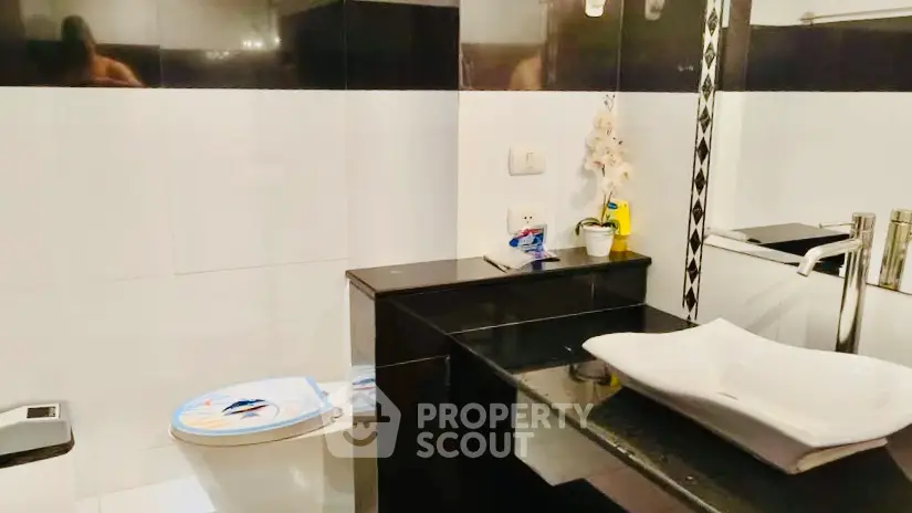 Modern bathroom with sleek black and white design, featuring a stylish sink and contemporary fixtures.