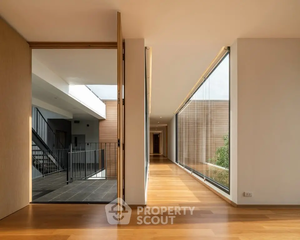 Modern hallway with wooden flooring and large windows in luxury building