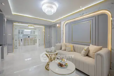 Luxurious living room with elegant decor and open kitchen layout, featuring a stunning chandelier and plush seating.