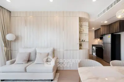 Modern living room with elegant decor and open kitchen layout featuring a washing machine and sleek appliances.