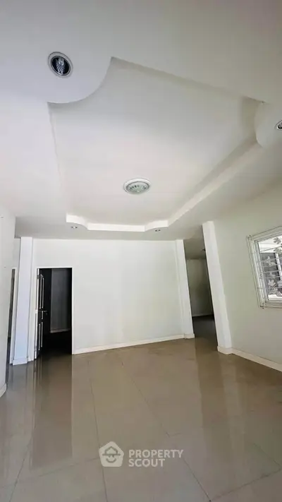 Spacious empty room with modern ceiling design and tiled floor