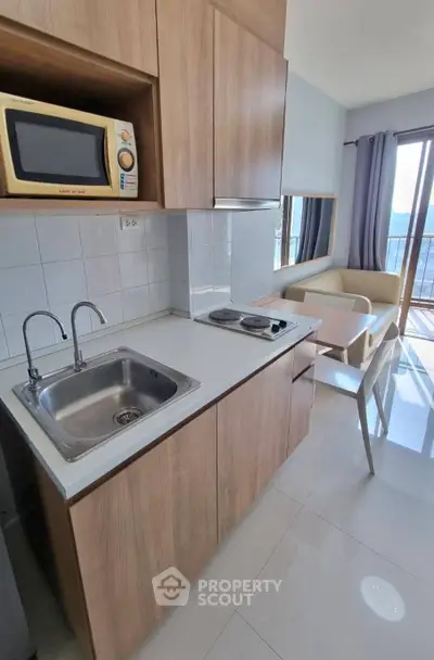 Modern kitchen with sleek cabinetry, built-in microwave, and cozy dining area with balcony view.