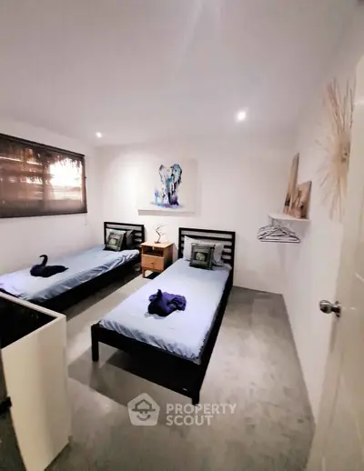 Modern twin bedroom with stylish decor and natural lighting, perfect for a cozy and comfortable living experience.