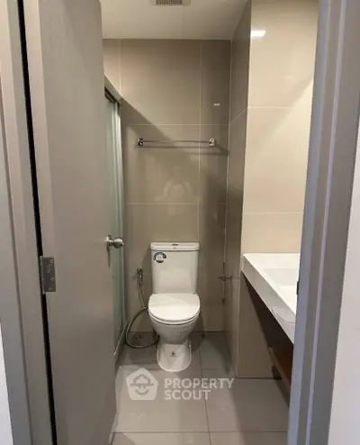 Modern bathroom with sleek design featuring a toilet, shower, and sink in a compact layout.