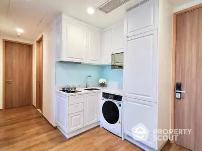 Compact modern kitchen with white cabinetry, built-in appliances, and wood flooring, ideal for urban living.