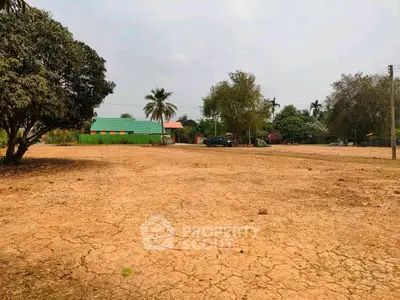 Expansive plot of land with potential for development, surrounded by lush greenery and a serene environment.