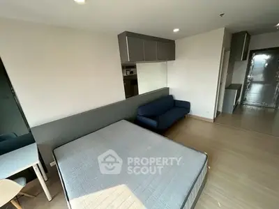 Modern studio apartment with sleek design, featuring a cozy bed, compact sofa, and stylish workspace.
