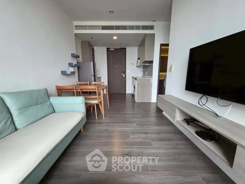 Modern living room with sleek furniture and open layout, featuring a wall-mounted TV and stylish flooring.