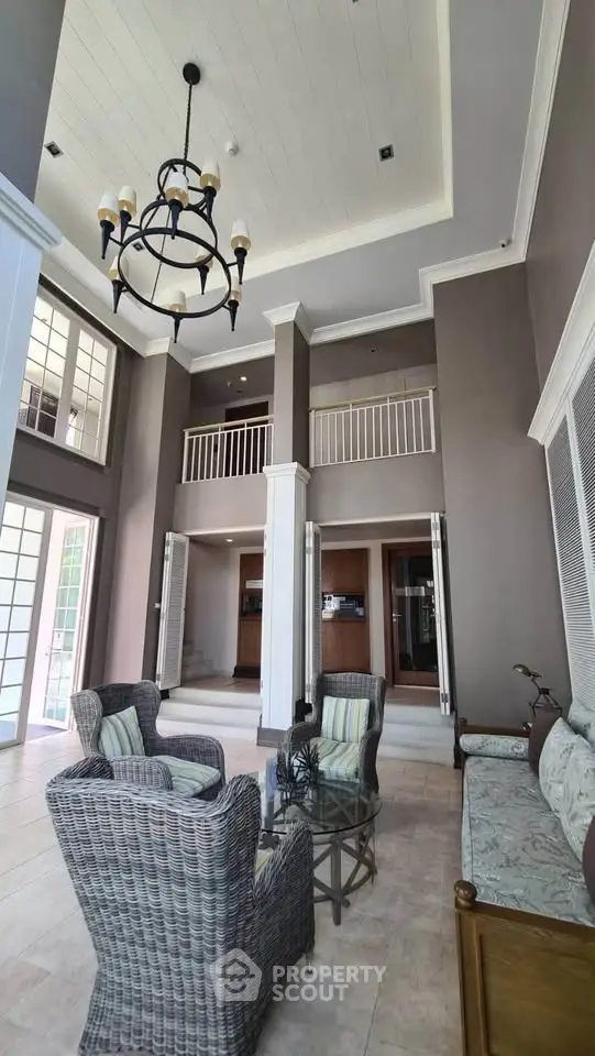 Luxurious high-ceiling living room with elegant chandelier and stylish furniture in a modern home.