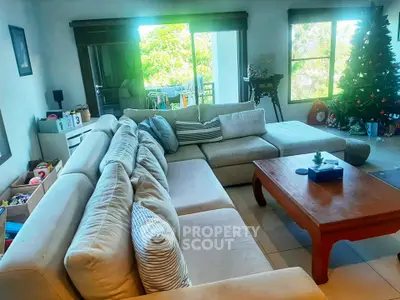 Spacious living room with large sectional sofa and Christmas tree, perfect for family gatherings.