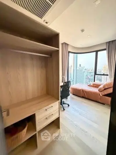 Modern bedroom with city view, featuring a cozy bed and a study area with a desk and chair.
