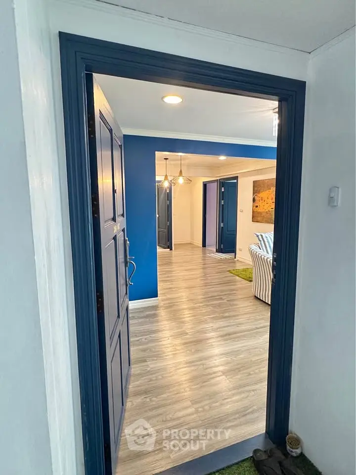 Stylish modern apartment entrance with blue accents and wood flooring