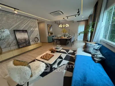 Luxurious modern living room with elegant decor and open dining area, featuring stylish furniture and large windows.