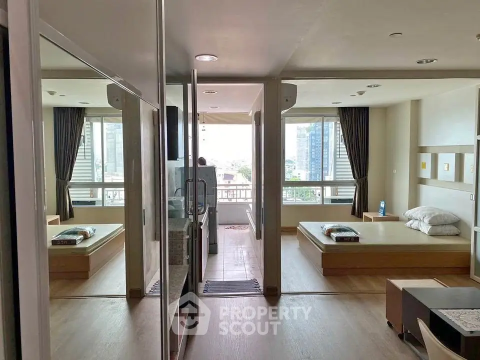 Spacious modern bedroom with large windows and city view, featuring minimalist decor and natural light.