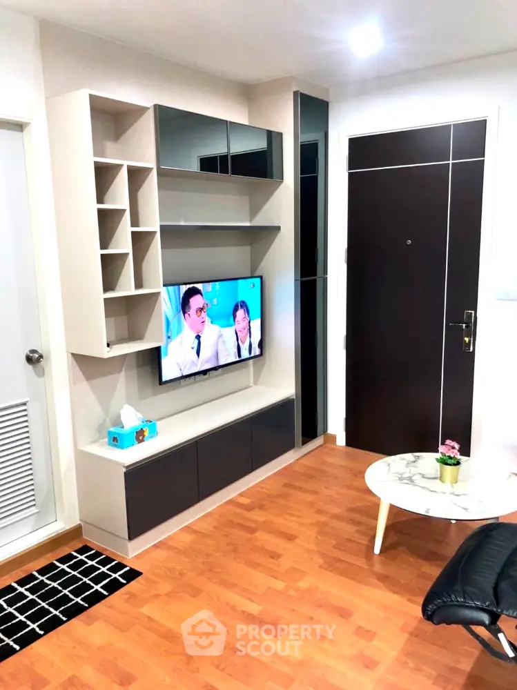Modern living room with custom shelving unit, mounted flat-screen TV, and elegant wood flooring, complemented by a chic marble coffee table.