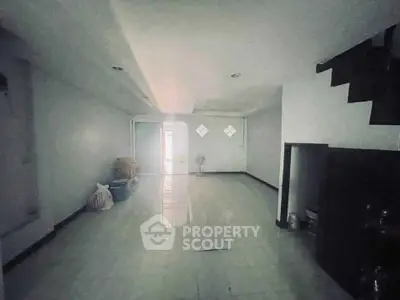 Spacious unfurnished room with tiled flooring and staircase, ideal for customization.