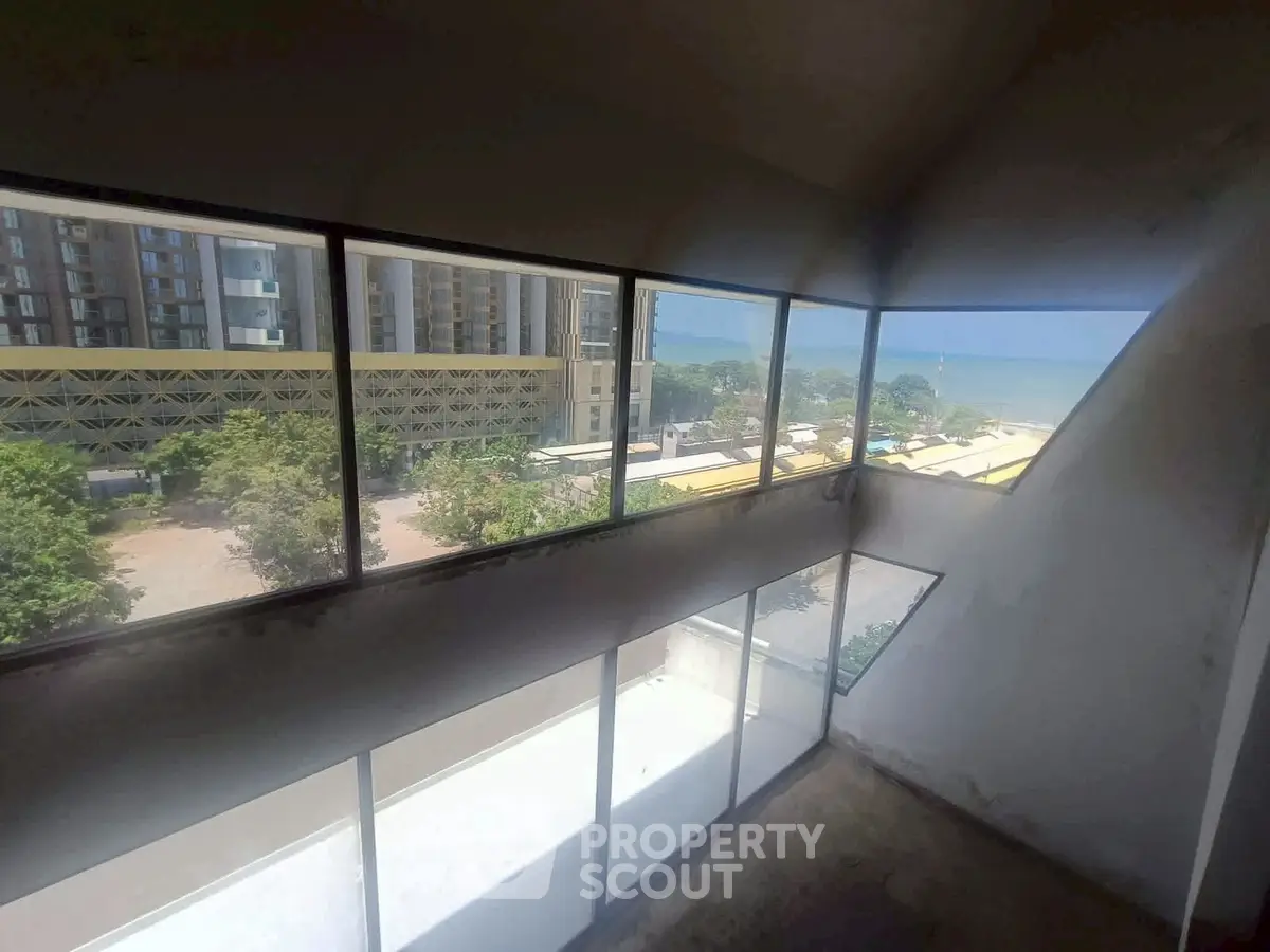 Stunning panoramic view from a modern high-rise apartment with expansive windows overlooking the city and sea.