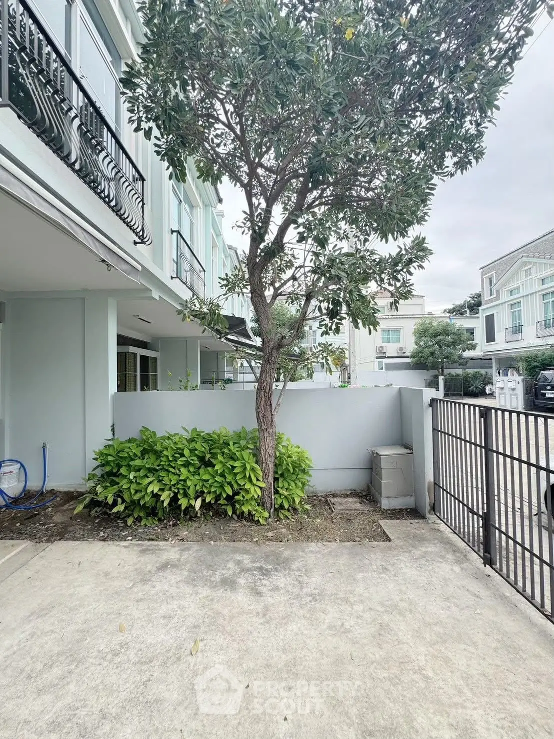 Charming residential building exterior with lush greenery and gated entrance