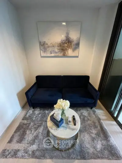 Chic living room with plush navy sofa, elegant artwork, and modern decor in a cozy apartment setting.