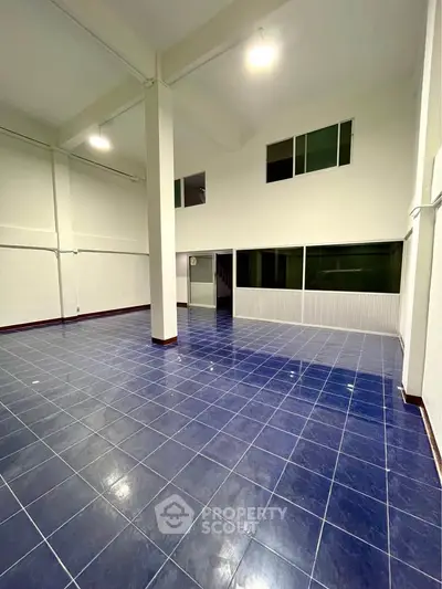 Spacious open-plan interior with high ceilings and blue tiled flooring, ideal for versatile use.