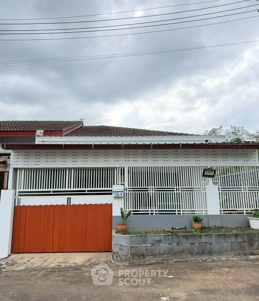 Charming single-story house with gated entrance and potted plants, perfect for cozy living.