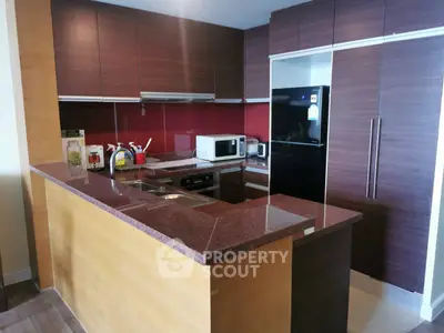 Modern kitchen with sleek cabinetry and appliances, featuring a stylish red backsplash and granite countertops.