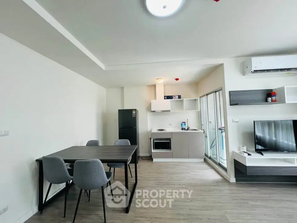 Modern open-plan living room with kitchen, dining area, and sleek furniture in a bright apartment.