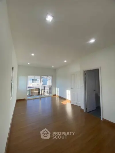 Spacious empty room with wooden flooring and large windows for natural light