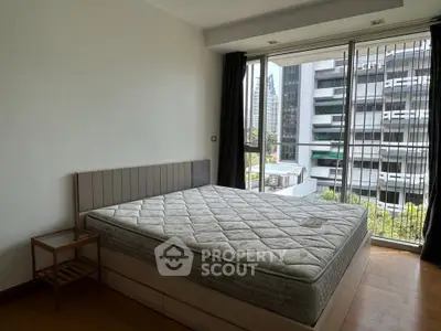 Spacious bedroom with large windows offering city views, featuring a comfortable bed and modern design.