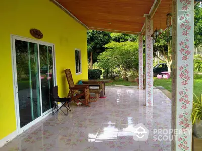 Charming patio with floral tiles and vibrant yellow wall, perfect for outdoor relaxation.