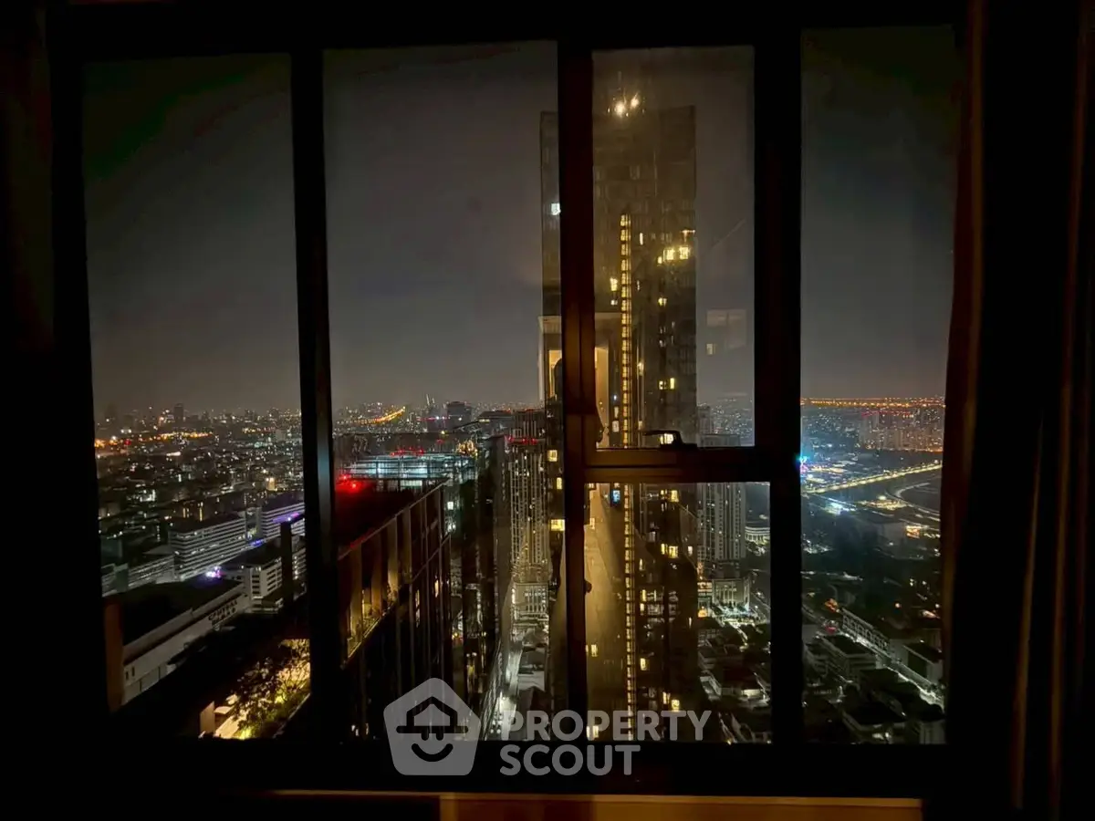 Stunning cityscape view from high-rise apartment window at night, showcasing vibrant urban lights.