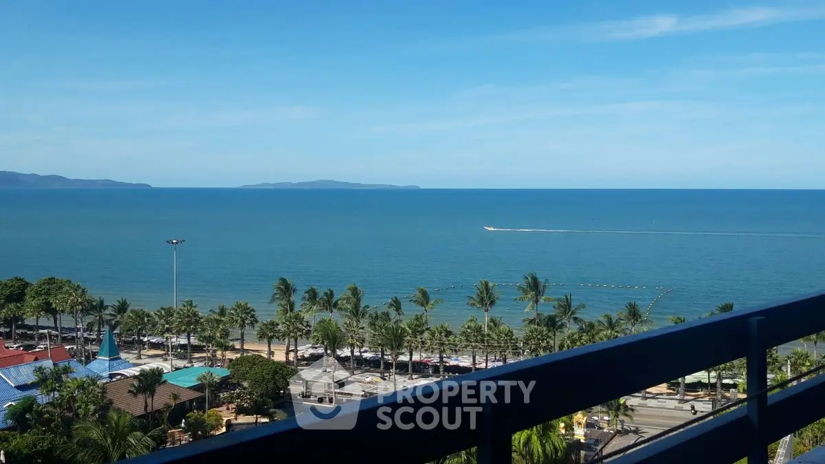 Stunning ocean view from a high-rise balcony with palm trees and clear blue sky.
