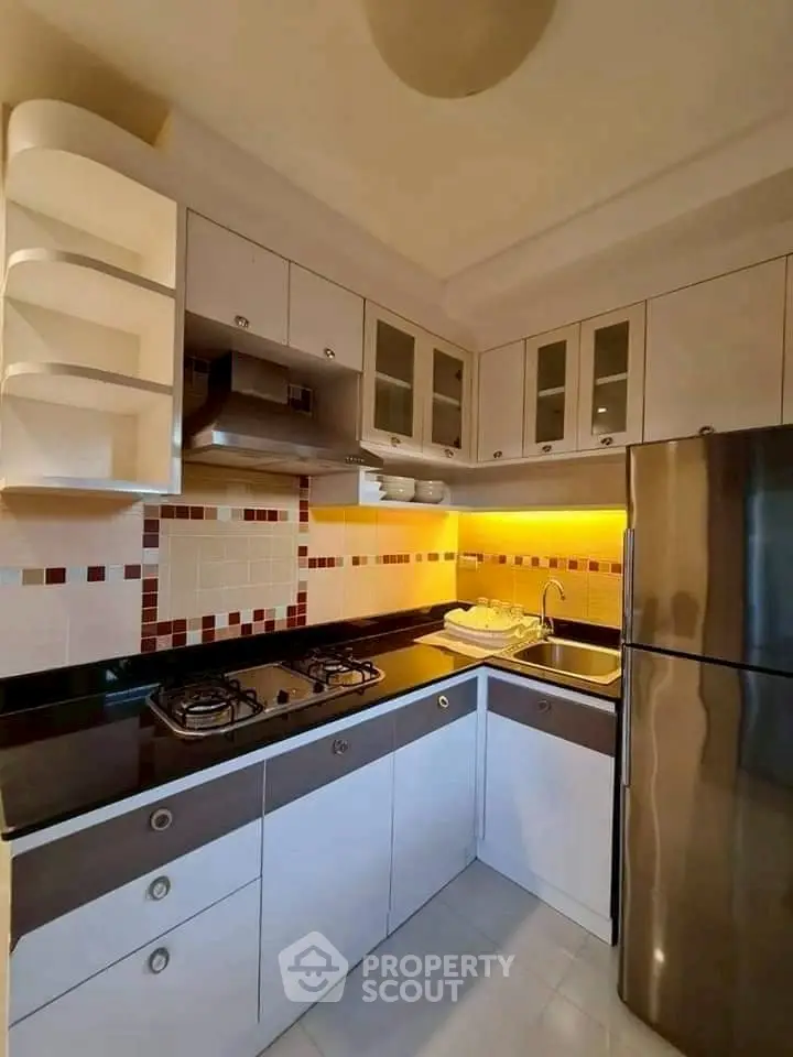 Modern kitchen with sleek cabinets, gas stove, and stainless steel fridge