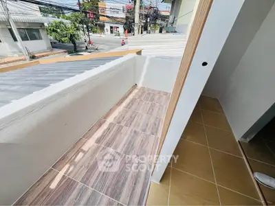 Charming small balcony with tiled flooring and street view, perfect for cozy outdoor relaxation.