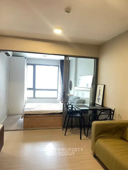Modern studio apartment with open layout, featuring a cozy living area and a bright bedroom with large windows.