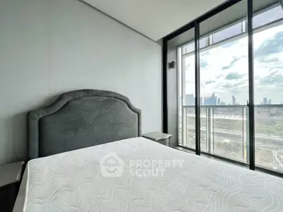 Modern bedroom with city view and large windows in a high-rise apartment