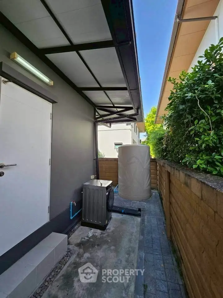 Modern exterior with sleek design and utility area, featuring a water tank and air conditioning unit.