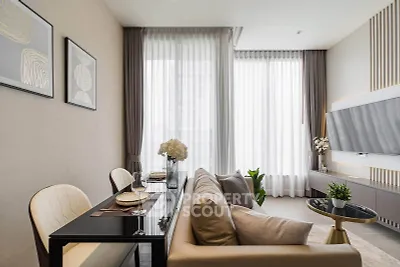 Modern living room with elegant decor and large windows, featuring a cozy dining area and stylish furnishings.