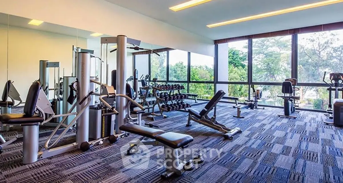Spacious modern gym with large windows and state-of-the-art equipment in luxury real estate property.