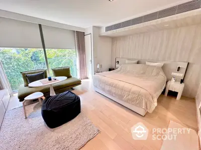 Luxurious bedroom with modern decor and large window overlooking greenery.