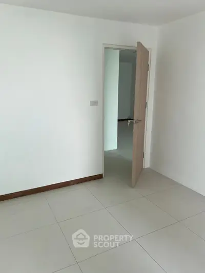 Spacious empty room with open door and tiled flooring in modern apartment