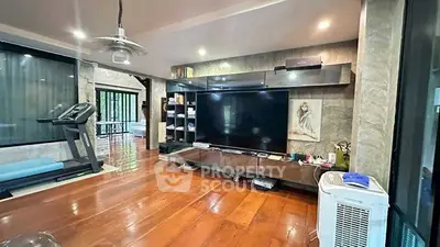 Spacious living room with modern entertainment setup and exercise equipment.