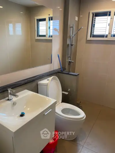 Modern bathroom with sleek fixtures and large mirror in contemporary home.