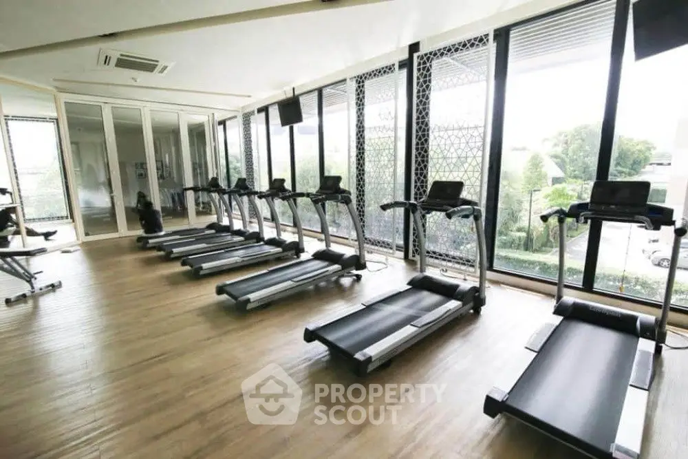 Spacious gym with modern treadmills and large windows offering a scenic view.