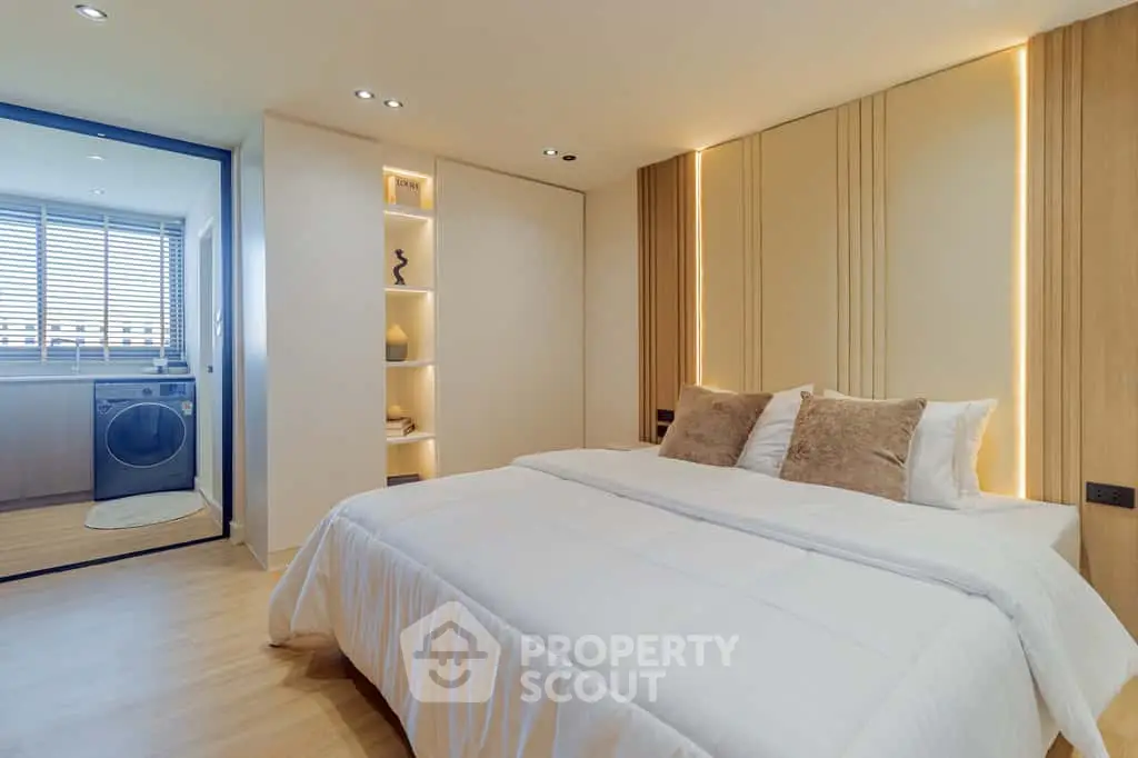 Luxurious bedroom with modern design and in-room laundry area, featuring elegant lighting and cozy bedding.