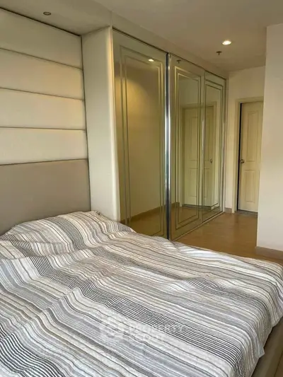Spacious bedroom with mirrored wardrobe and cozy bed in modern apartment.