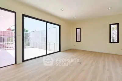 Spacious empty room with large sliding glass doors leading to a bright balcony.