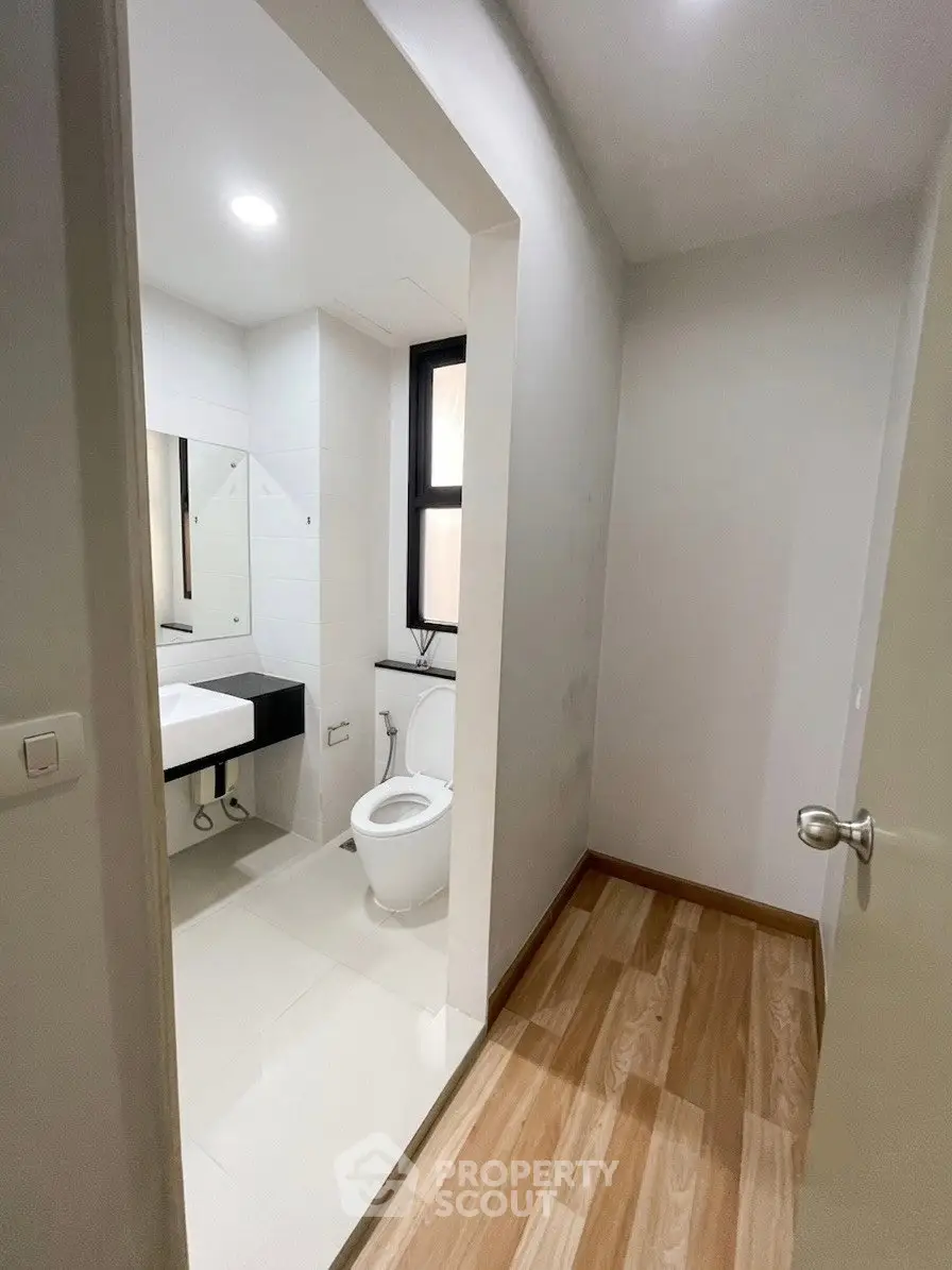Modern bathroom with sleek design and wooden flooring in a contemporary apartment.