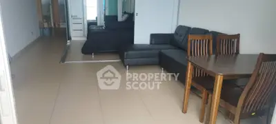 Modern open-plan living room with sleek black sofa and dining area