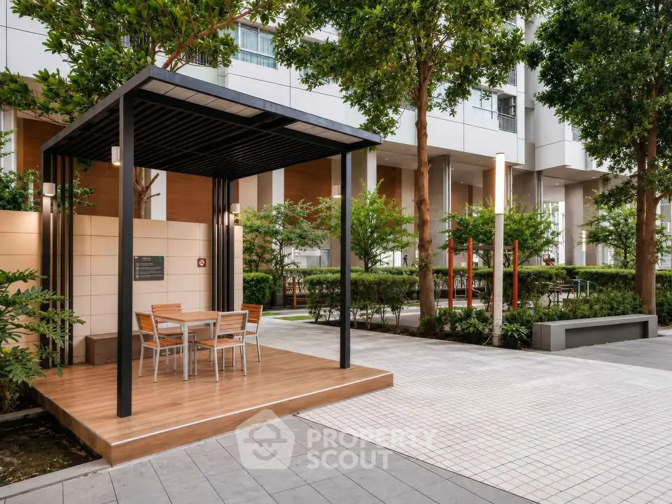 Modern outdoor seating area in a residential complex with lush greenery and sleek design.